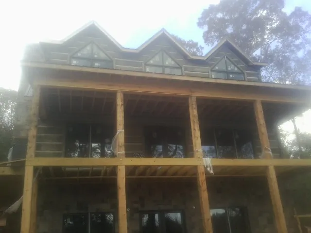 Dormers and porch framing on a large log home under construction — Roof Coating work by our crew in Empire